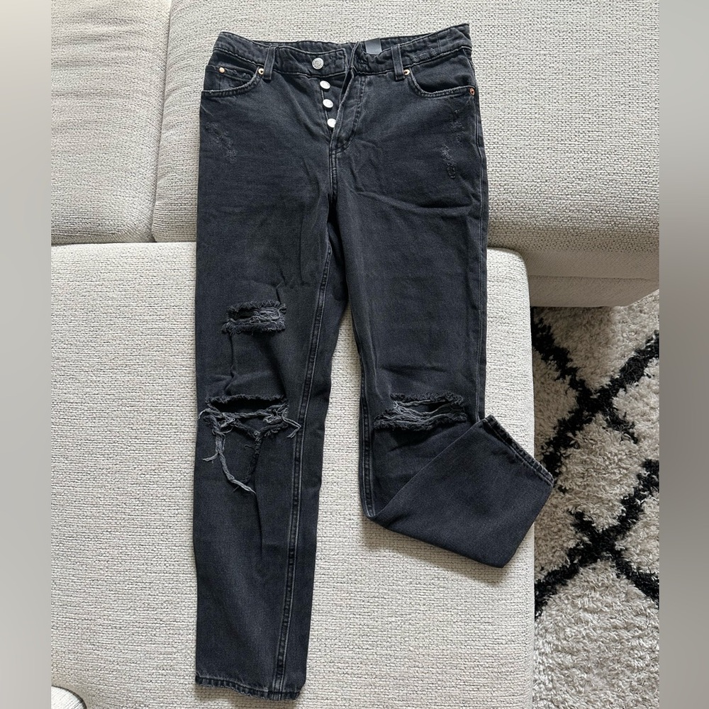 Black H&M jeans with rips and multiple buttons on front.